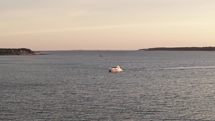 Sunset light over South Carolina coast, calm water surrounds docked fishing boats, aerial telephoto orbit
