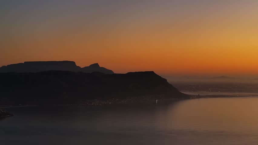 Aerial view of serene coastal silhouette at sunset with majestic mountains and tranquil sea, Simon