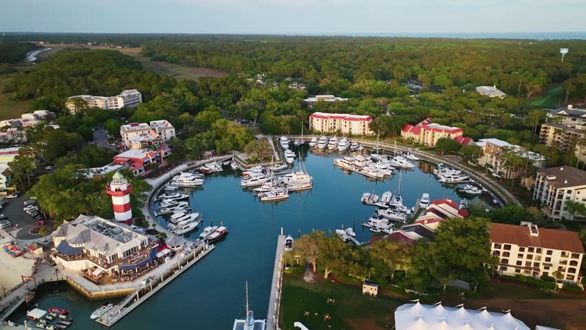 Overhead flyover of South Carolina harbor with curving boardwalk pier and boats, Harbour Town Pier South Carolina USA