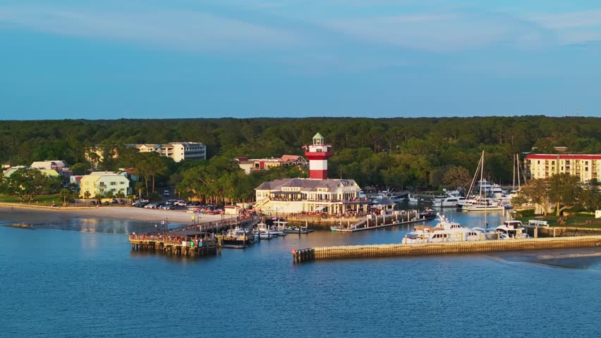 Wide panoramic establishing of marina harbor and lighthouse in soft afternoon lighting, Harbour Town Pier South Carolina USA