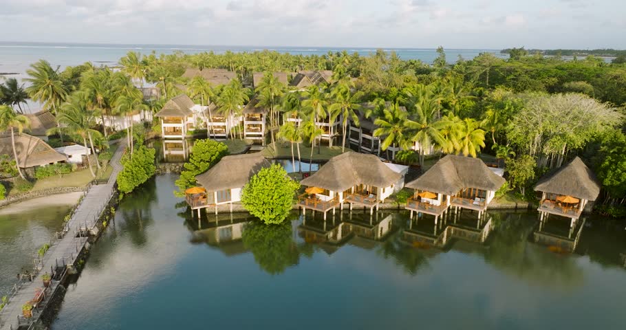 Aerial view of luxurious bungalows with palm trees by the tranquil ocean and serene lagoon, prince maurice, flacq, mauritius.