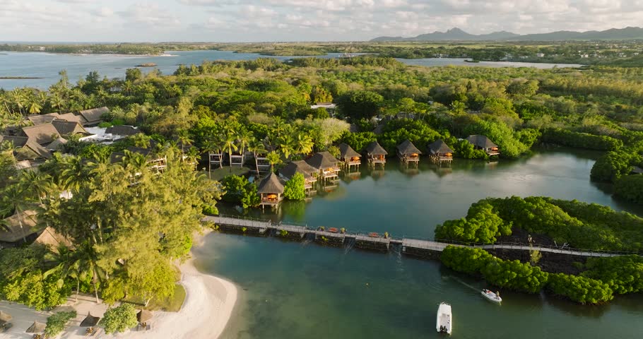 Aerial view of luxurious tropical resort with bungalows and palm trees by the tranquil white sand beach and lagoon, Prince Maurice, Flacq District, Mauritius.