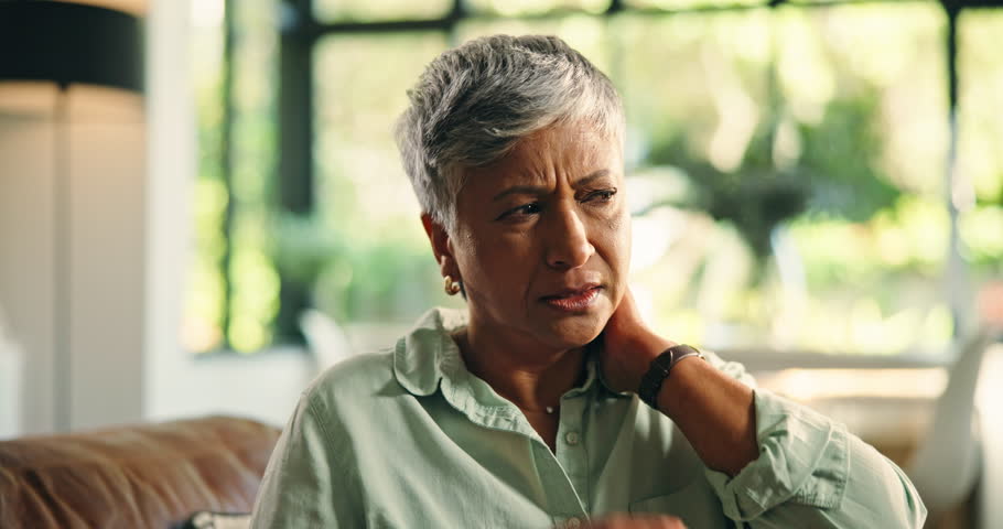 Home, sore and woman with neck pain, massage or discomfort of injury, hurt or bad posture in lounge. Tension, swollen and stiffness of joints, osteoarthritis and muscle strain for old person in house