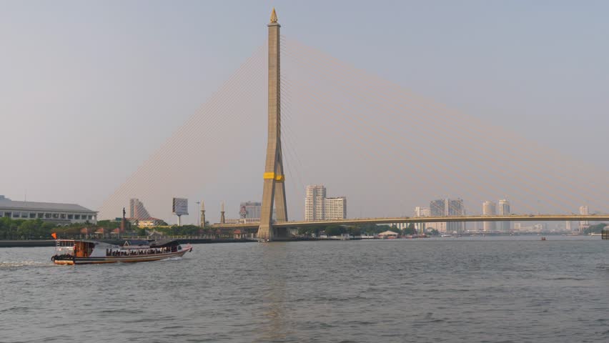 A boat crossing the Chao Phraya River under the Rama VIII Bridge in Bangkok, Thailand