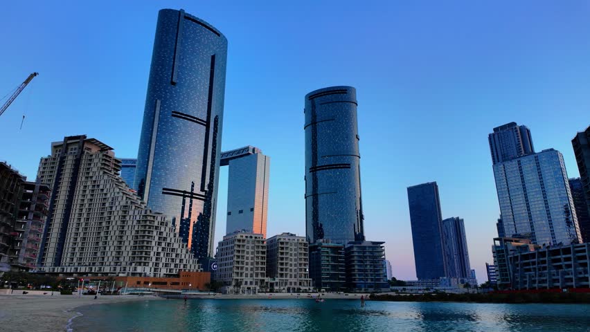 Al Reem Island with office and apartment towers in Abu Dhabi United Arab Emirates at twilight as seen from the beach