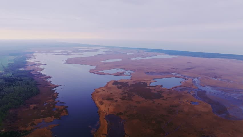 Aerial wide shot of Pape Lake wetlands, morning mist, Baltic Sea in the distance