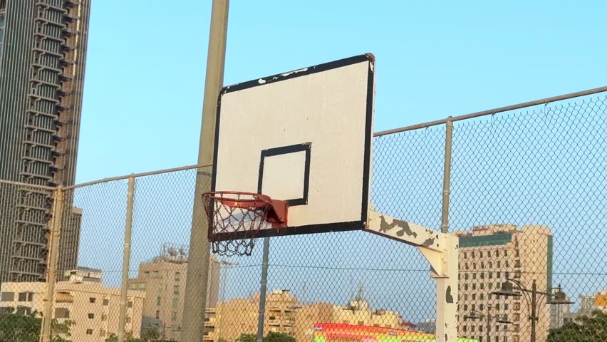 Basketball hitting the hoop on a vintage outdoor court with city skyline. Urban sports moment ideal for ads, promos, and creative storytelling.