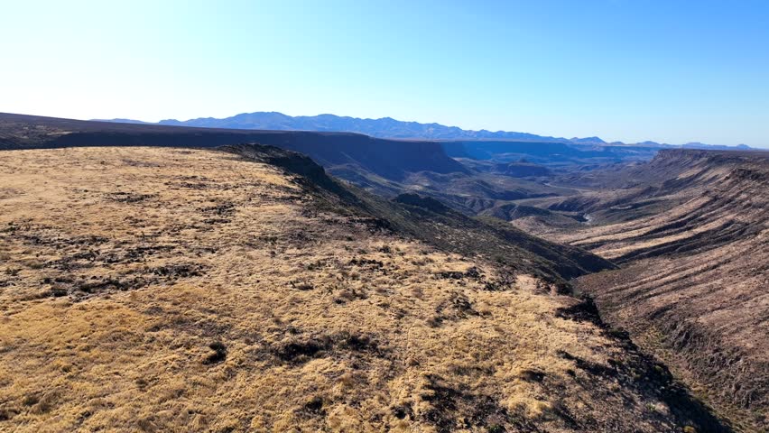 Aerial view of rugged canyon and expansive valley under clear sky, Agua Fria National Monument, Arizona, United States.