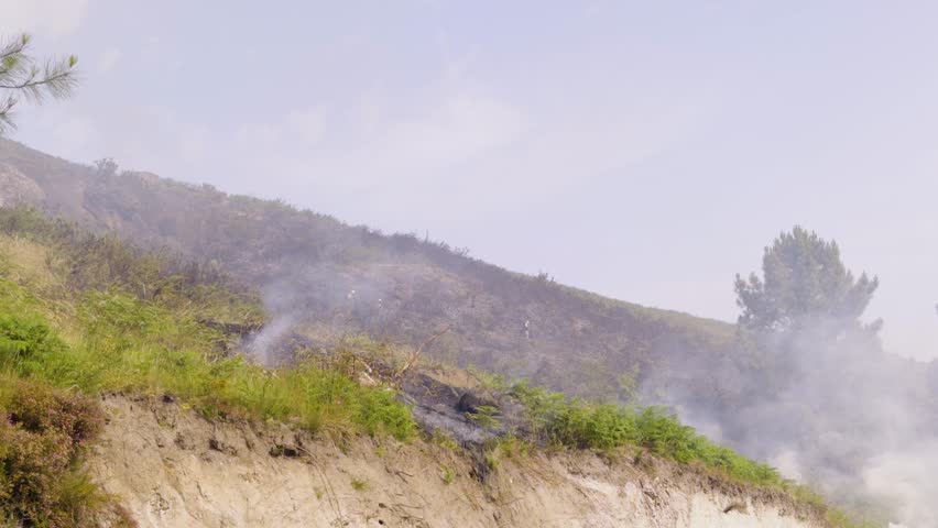 Firefighters descend from the still smoking mountain after extinguishing a forest fire.