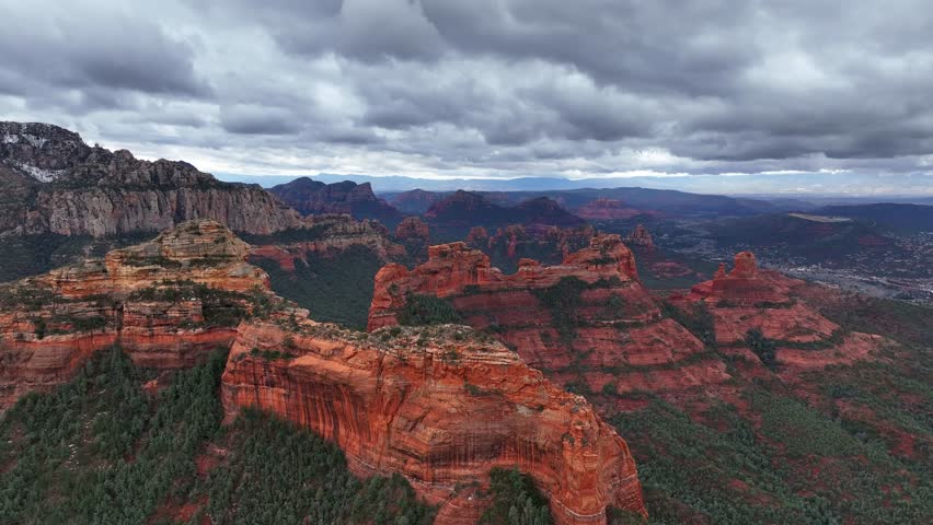 Aerial view of rock formations and mountains with a valley under a cloudy sky, Sedona, Arizona, United States.