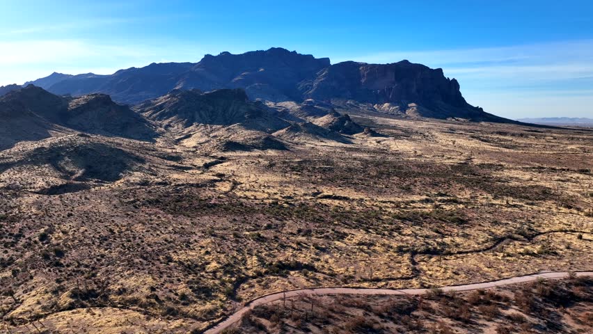 Aerial view of majestic rugged mountains and barren desert under a sunny blue sky, Apache Junction, Pinal County, Arizona.