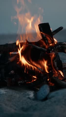 Woman Walking On The Beach Behind A Bonfire Burning 