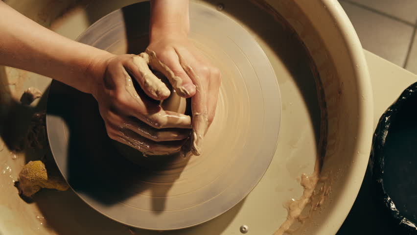 Woman potter works with clay on master class in studio. Working process in ceramic workshop. Potter making vase on pottery wheel. Handmade concept. 