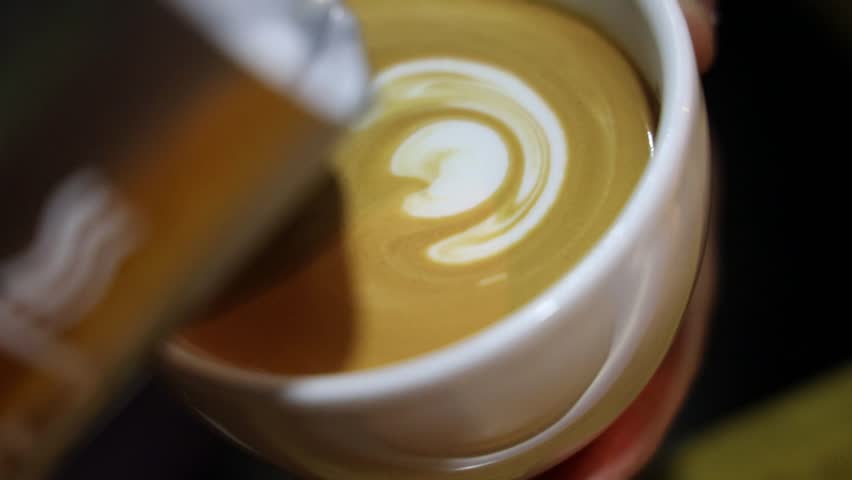 A beautifully crafted latte with foam art spelling out a word in creamy detail, served in a warm cup
