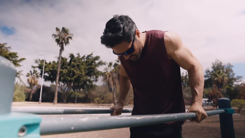 Fit Middle-Aged Man Doing Dips on Parallel Bars at Outdoor Calisthenics Gym