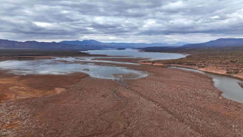 Aerial view of tranquil Theodore Roosevelt Lake surrounded by majestic mountains and a cloudy sky, Upper Salt River Recreation Site, Roosevelt, Arizona, United States.