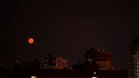 Crimson lunar orb ascending above shadowy urban skyline, casting ethereal glow across darkened metropolitan rooftops during nocturnal hours - Powered by Shutterstock - Get 15% off with code: PIKWIZARD15