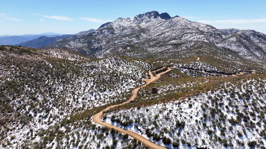 Aerial view of four peaks covered in snow surrounded by majestic forests and rugged mountains, Apache Junction, Arizona, United States.
