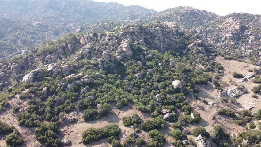 A drone view of South Türkiye's arid, Mediterranean-like hills with terra tones and sparse vegetation, captured during a scenic summer road trip.
