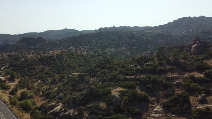 A drone view of South Türkiye's arid, Mediterranean-like hills with terra tones and sparse vegetation, captured during a scenic summer road trip.