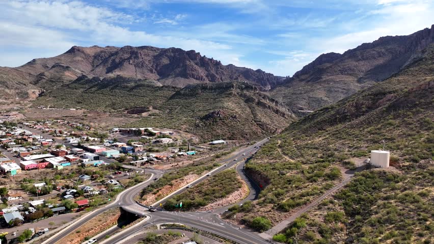 Aerial view of scenic mountains and rugged hills alongside a winding road with residential areas, Superior, Pinal County, Arizona, United States.