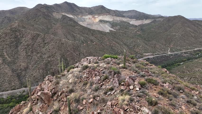 Aerial view of the rugged copper mine surrounded by majestic mountains and a dusty road in a vast arid valley, Pinal County, Arizona, United States.