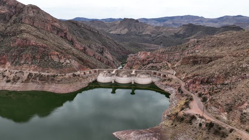 Aerial view of serene San Carlos Lake with majestic Coolidge Dam and rugged mountains, Pinal County, Arizona, United States.