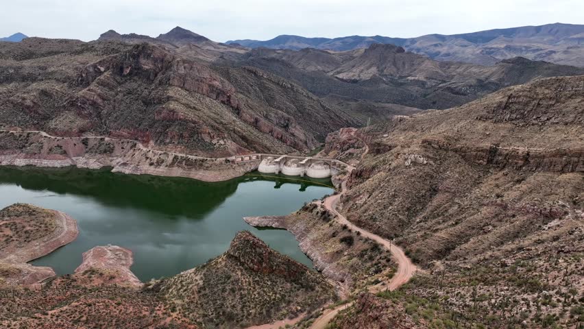 Aerial view of san carlos lake and coolidge dam surrounded by rugged mountains and arid desert landscape, pinal county, arizona, united states.