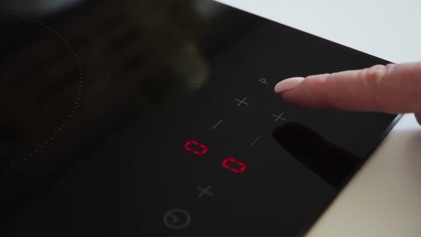 Hand turns on the induction cooker for cooking. Finger touch sensor button on the induction or electric lever.