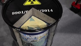 Radioactive waste barrel cut open to reveal layered contents of syringes gloves textiles and circuit boards highlights dangers of improper hazardous material disposal and cross-contaminated waste - Powered by Shutterstock - Get 15% off with code: PIKWIZARD15