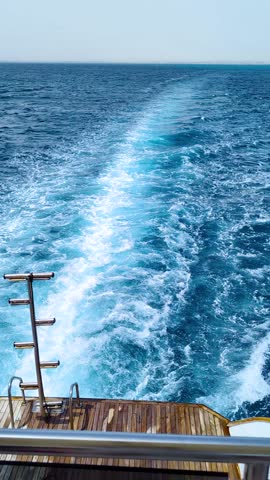 Sea liner engine tracks viewed from private yacht, showcasing deep blue water with sea foam. Beautiful cruise travel vertical concept, relaxing vacation theme in the warm Red Sea. Voyage adventure