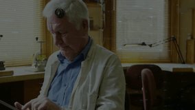 Craftsman with loupe tapping tablet at bench displaying finance charts and analyzing metric trends. Analytical, senior, innovation, technology, industry, workshop, focus - Powered by Shutterstock - Get 15% off with code: PIKWIZARD15