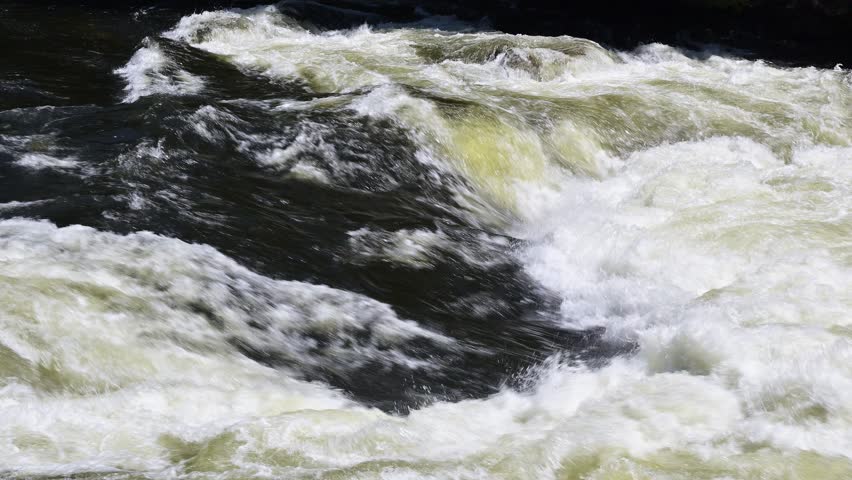 Roaring mountain river swollen in springtime crashing on whitewater flow of chaos