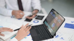 Two people are working on a laptop and a notebook. One person is writing on the notebook while the other person is looking at the laptop. The laptop has a screen displaying graphs and charts - Powered by Shutterstock - Get 15% off with code: PIKWIZARD15