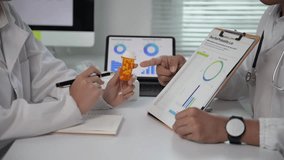 Two doctors are looking at a chart and a bottle of pills. One of the doctors is pointing to the pills - Powered by Shutterstock - Get 15% off with code: PIKWIZARD15