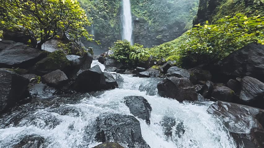 Macro shot of water gliding over smooth rocks, detailed bubbles and reflections forming a relaxing loop scene. No audio.