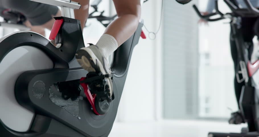 Bike, fitness and legs of person in spin class for cardio training, challenge or performance. Endurance, exercise and sneakers with feet of athlete in gym for indoor cycling or stationary workout