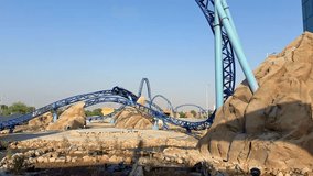 Bright blue roller coaster rushes through loops and curves in a desert-themed amusement park. Thrilling ride, steep turns, and adrenaline-filled fun in a scenic outdoor setting - Powered by Shutterstock - Get 15% off with code: PIKWIZARD15
