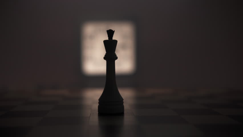A man hand moves back a chess piece against a background of a glowing clock