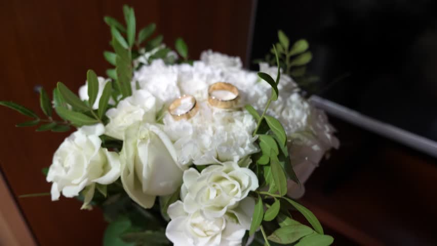 Two gold wedding rings on a flower of a wedding bouquet. Preparation for the wedding ceremony.