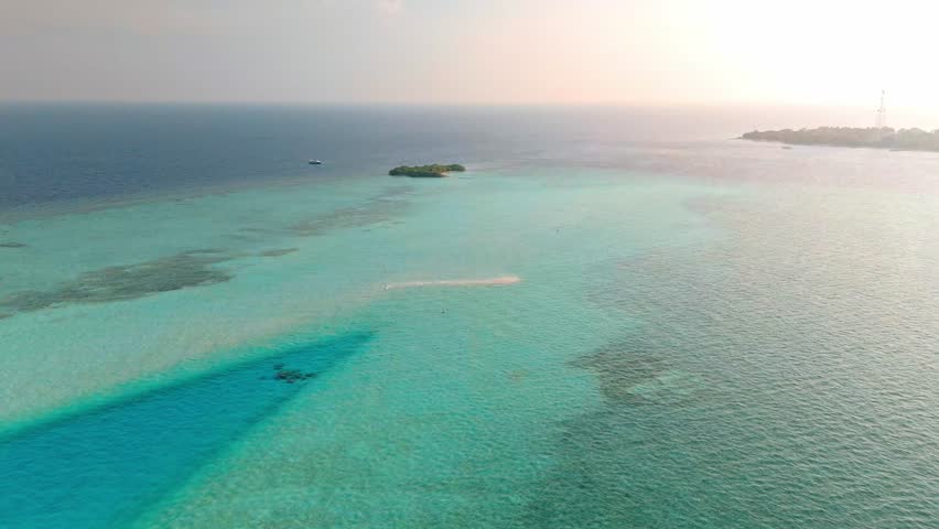 An awe-inspiring aerial drone view captures the Rasdhoo Sandbanks glowing under the soft, golden light of sunset in the Maldives.