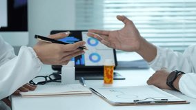 Two medical professionals in lab coats analyze charts and data on a laptop, engaging in a focused discussion - Powered by Shutterstock - Get 15% off with code: PIKWIZARD15