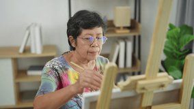 Senior woman artist painting abstract artwork on canvas in bright creative studio, showcasing passion for art and dedication to artistic expression - Powered by Shutterstock - Get 15% off with code: PIKWIZARD15
