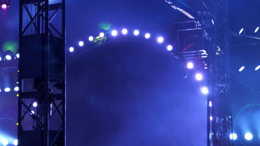 Multicolored spotlights blink in a semicircle on the stage in the smoke. A concert or circus performance. A fire breaks out in the foreground. Circus background. Concert lighting.