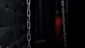Close-up of hanging chains in a dark room with multicolored light bulbs in the background. The chains swing from side to side.  - Powered by Shutterstock - Get 15% off with code: PIKWIZARD15