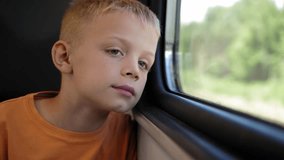 Close-up of a little boy riding a train and looking out the window. A child is a passenger, a boy travels by train in the summer. - Powered by Shutterstock - Get 15% off with code: PIKWIZARD15