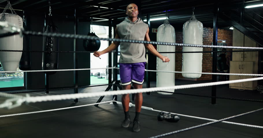 Active, black man and jump with rope at gym for fitness, cardio exercise or prepare for boxing match. Male person, skipping and equipment for workout, endurance training and performance for challenge