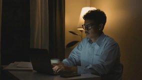 Asian man working on a laptop during nighttime hours.4k - Powered by Shutterstock - Get 15% off with code: PIKWIZARD15