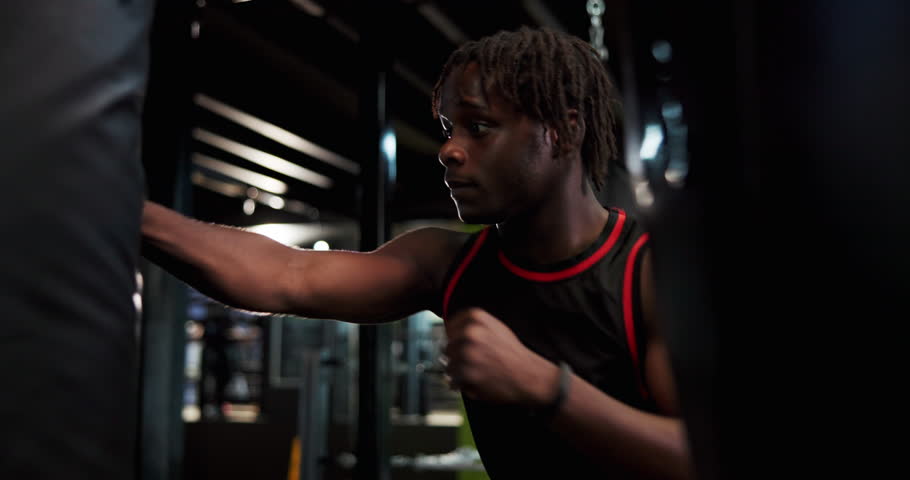 Boxing, sports and black man in gym for workout, cardio or training for MMA fight with challenge. Strong, exercise and African male athlete with power punching for self defense at fitness center.