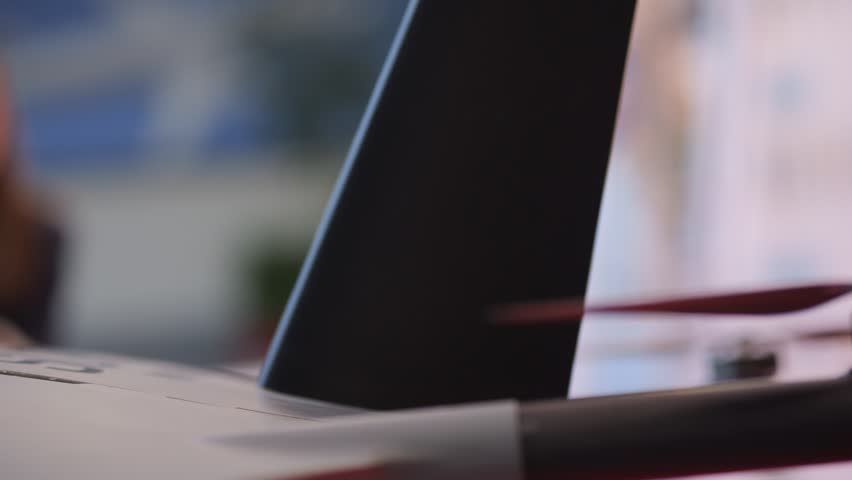 Black object with a red tip is on a white surface. The object is long and thin, and it is a part of a larger object. The image has a sense of motion and energy